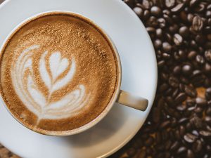 A cup of coffee with heart pattern in a white cup on wooden background
