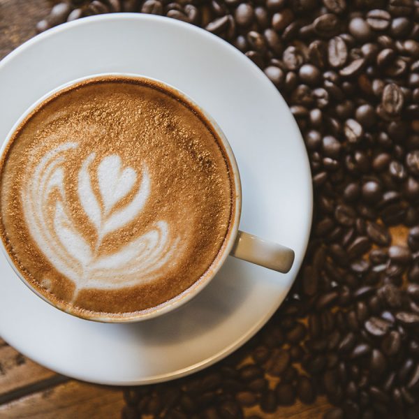 A cup of coffee with heart pattern in a white cup on wooden background