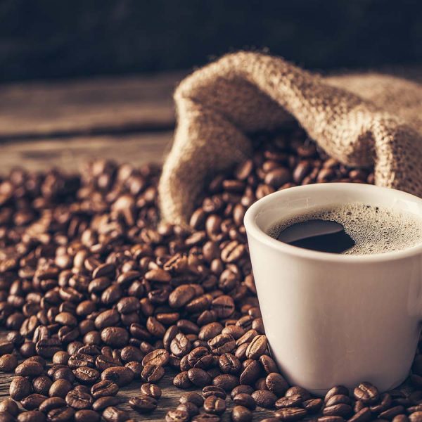 cup of coffee surrounded by beans