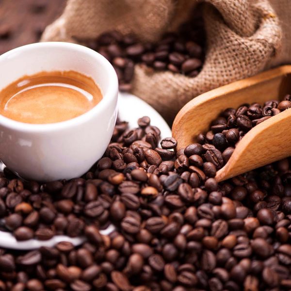 scoop of coffee beans surrounding a cup of espresso