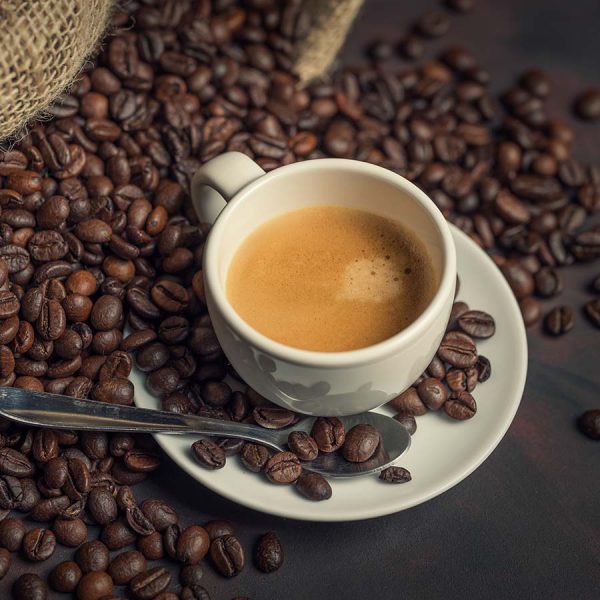 top view of espresso surrounded by coffee beans